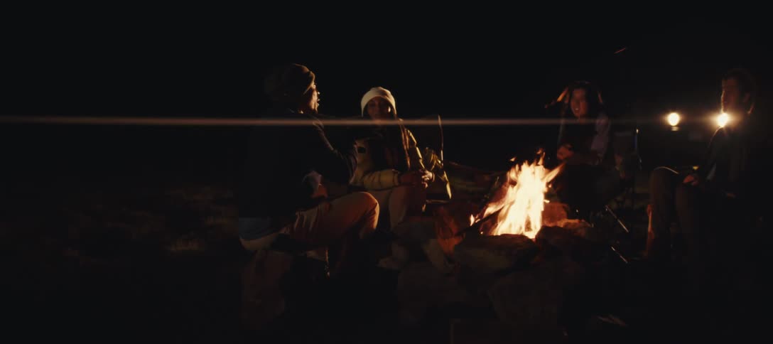 Friends talk around the campfire at night