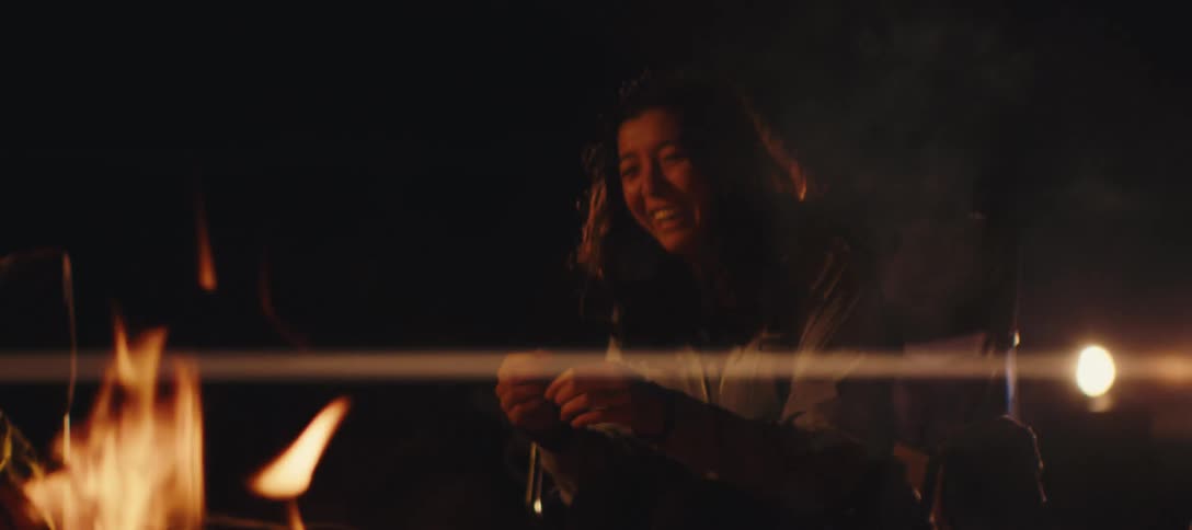 Friends talk and warm by the campfire