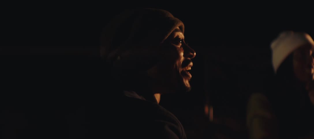 Two people laughing together near a campfire at night