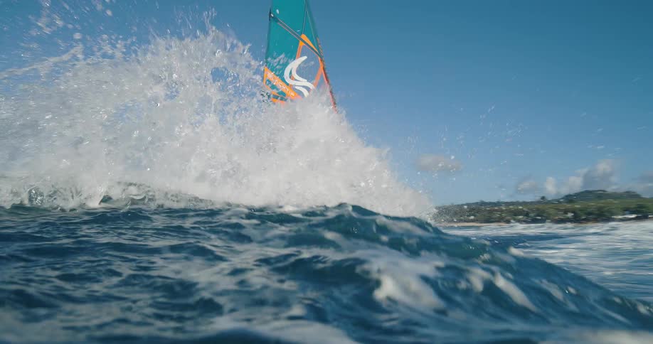 A young man windsurfs across the ocean surface during daytime
