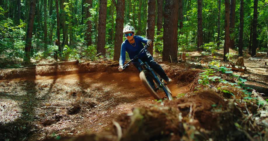 A mountain biker rides around a dirt trail curve in a dense forest