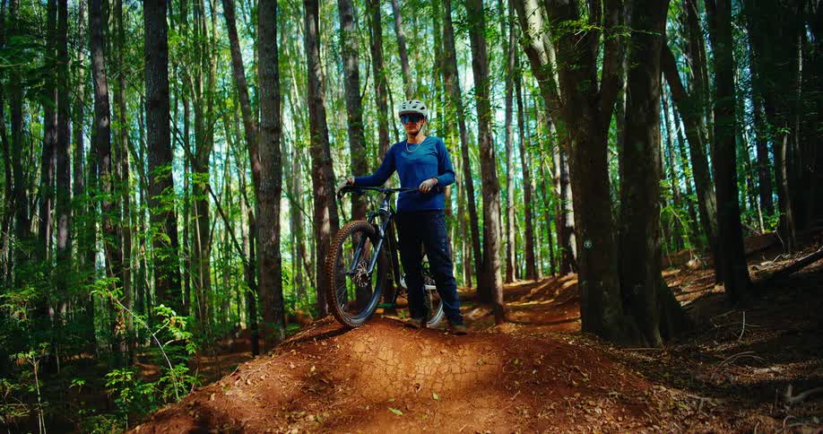 Cyclist with a bike stopped on a dirt trail in the forest wearing a helmet and protective glasses