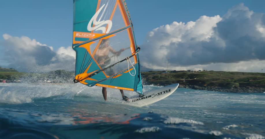 Man practices windsurfing balancing on the board over the waves