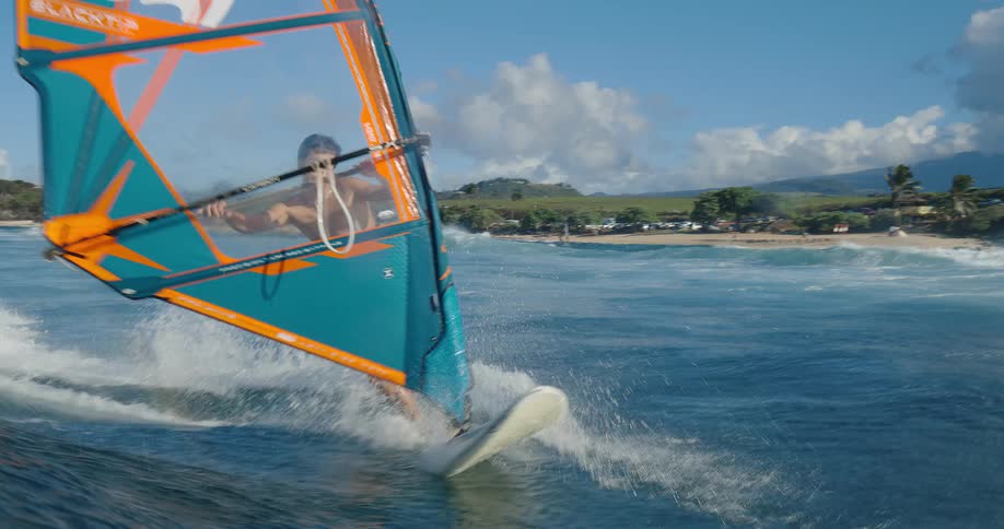 Male windsurfing through ocean waves on a clear bluesky day