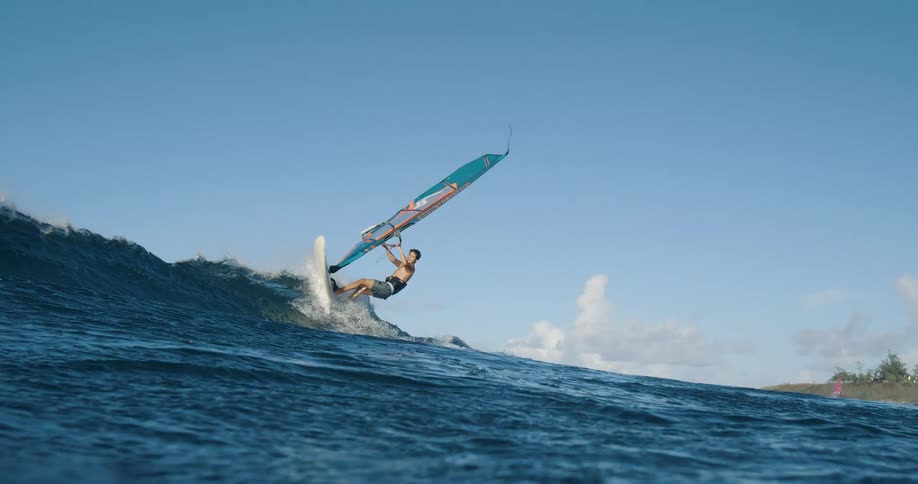 A man is windsurfing through ocean waves on a clear bluesky day
