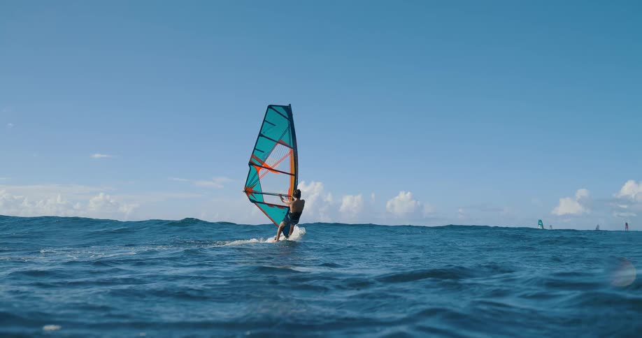 Windsurfer rides the sea with a blue and orange sail