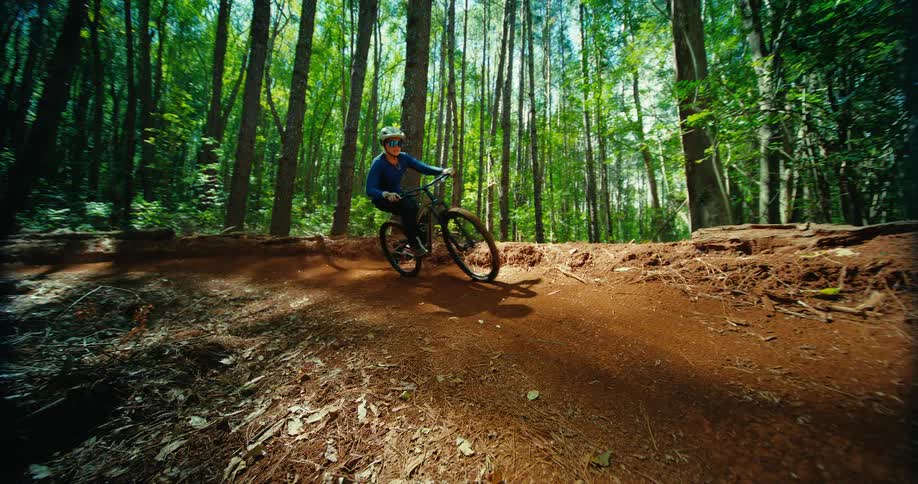 Cyclist wearing goggles and a helmet takes a fast turn on a dirt trail in the forest
