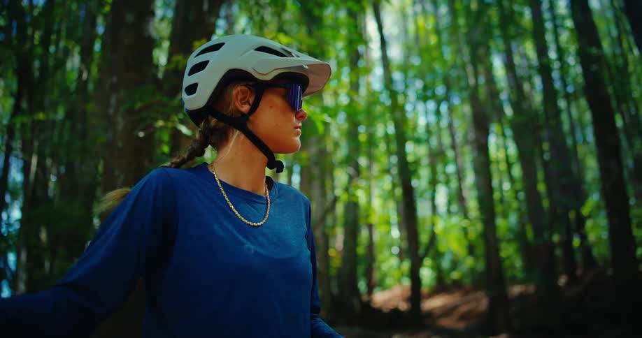 Close up portrait of a young female cyclist standing in a woodland area during daytime