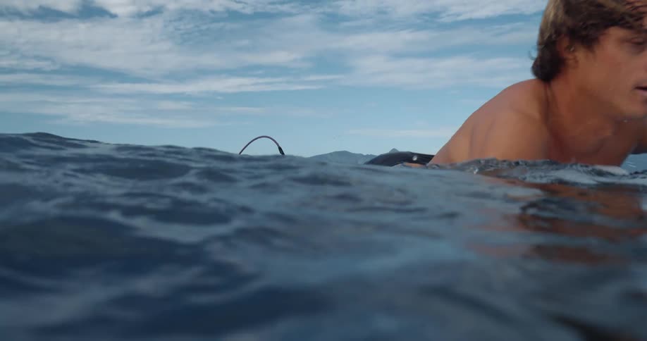 Male surfer paddling on his surferboard in the ocean
