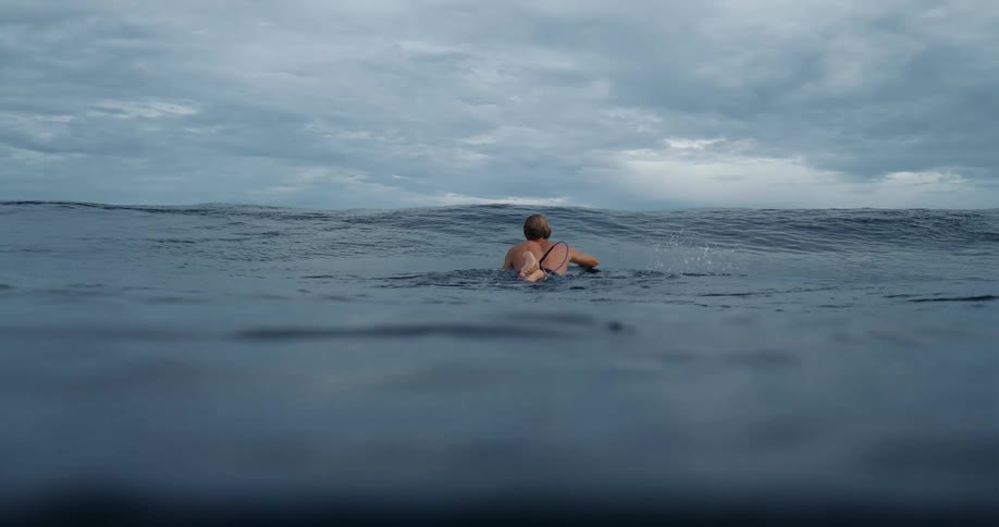 A surfer lying down on his board swimming towards the ocean waves