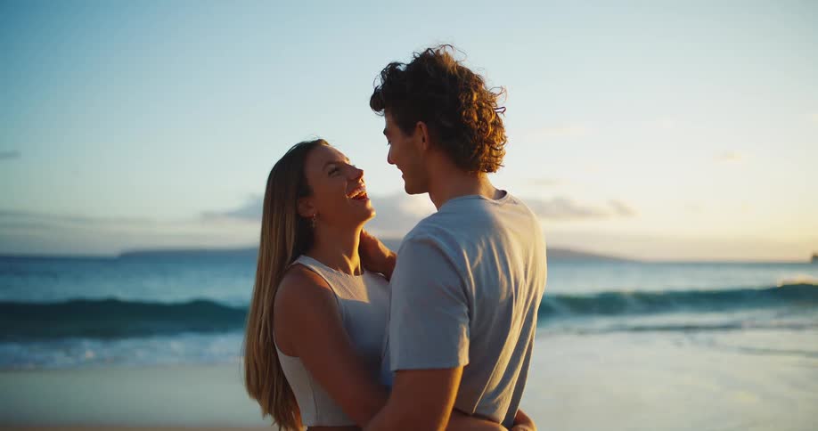 The couple smile and kiss on the beach