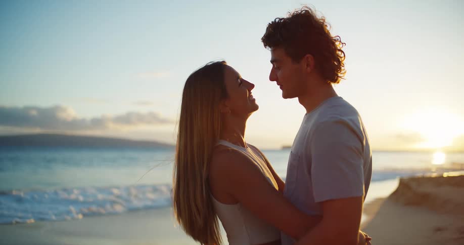 A young happy couple embraces on the beach at sunset