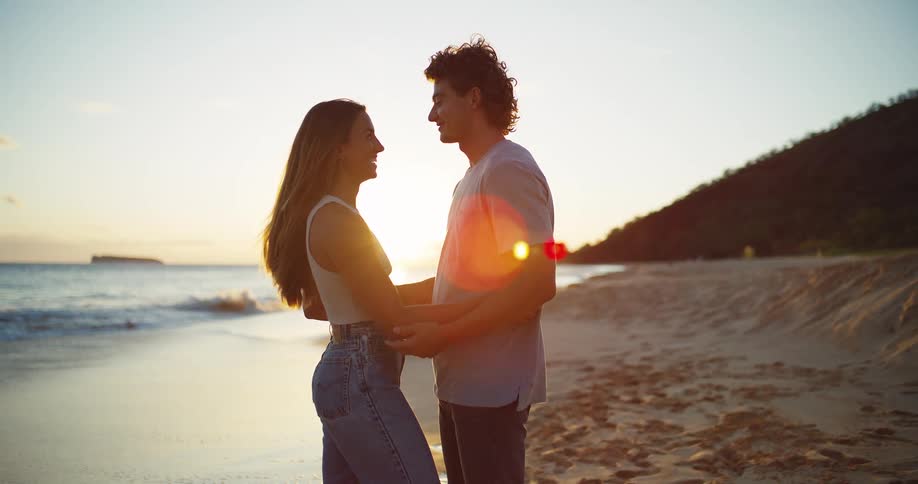 A young man and woman hug each other on the beach and share a kiss