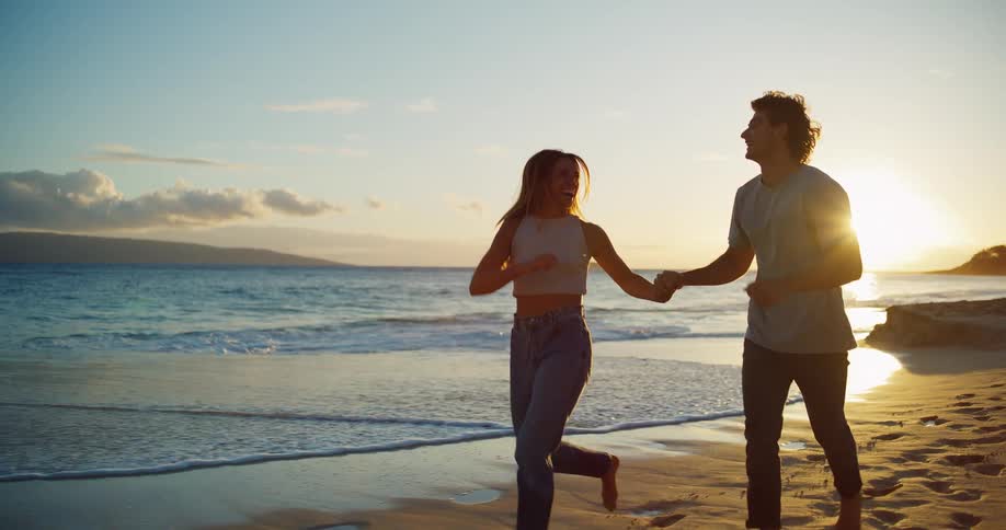The video shows a couple running handinhand along a sandy beach they are smiling and enjoying the beautiful sunset over the ocean