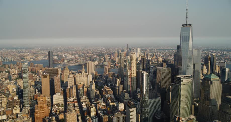 A sweeping aerial shot pans across the dense skyscraperfilled skyline of lower manhattan in new york city on a hazy day