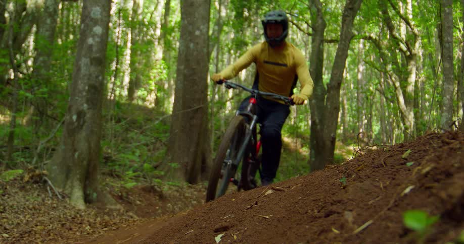 A person quickly rides their mountain bike along a forest trail