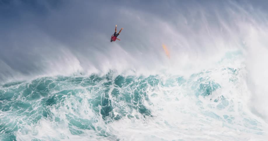 A man on a surfboard rides a large wave until its crashing then he flies off the surfboard