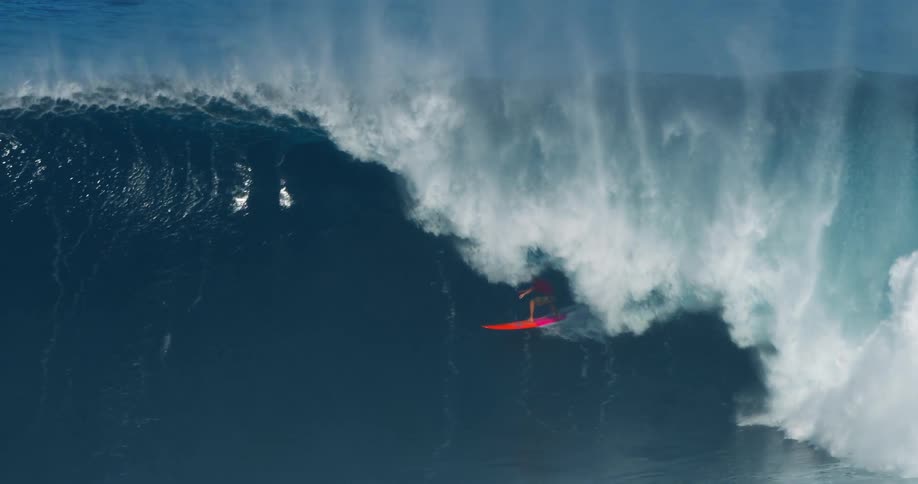 A young man surfs a huge ocean wave during daytime
