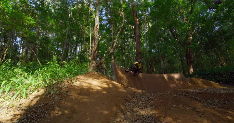 A mountain biker launches off a dirt jump in the forest