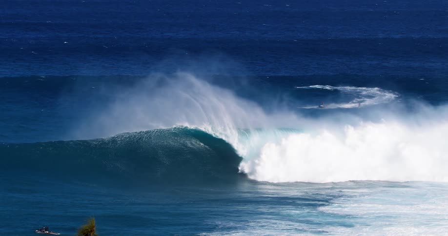 The video shows a large powerful ocean wave breaking with a surfer in the middle of it white water and sea spray are visible as the wave crashes