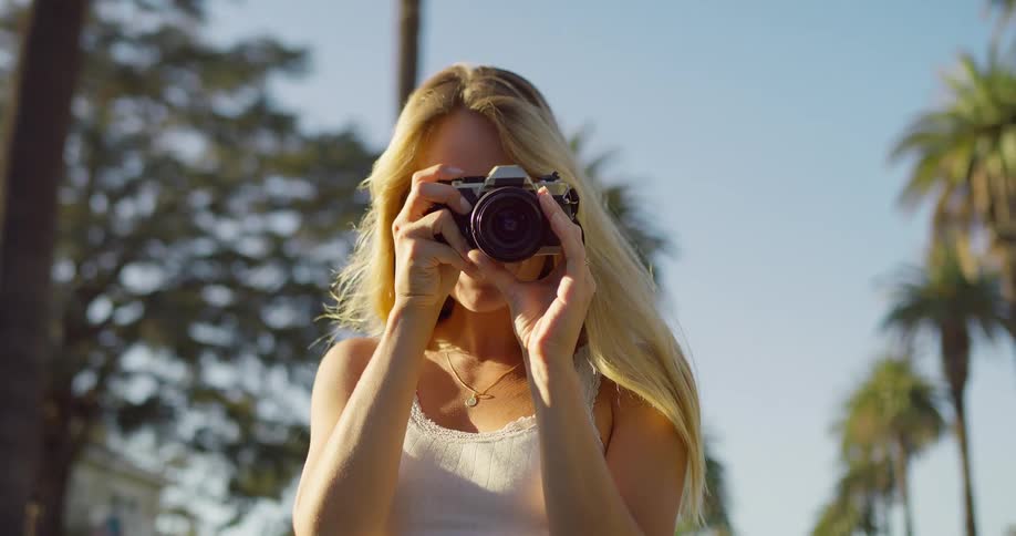 The woman snaps photos on a sunny day