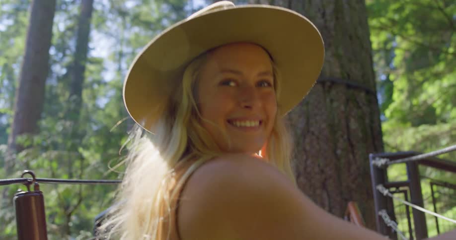 The woman smiles as she crosses the small bridge in the forest