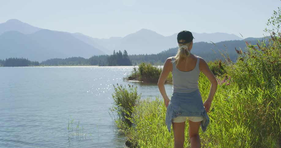 A woman walks up to the edge of a body of water