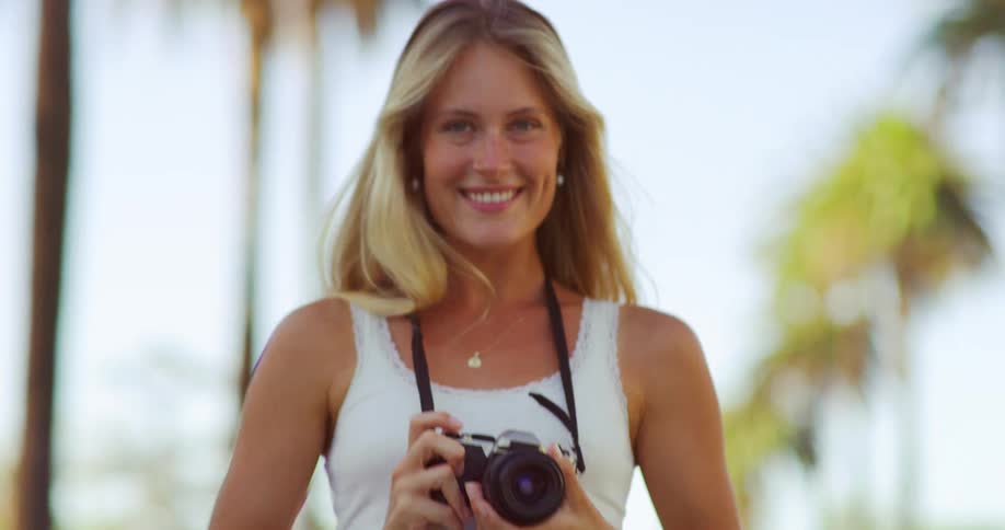 The woman is taking photos and smiling outside
