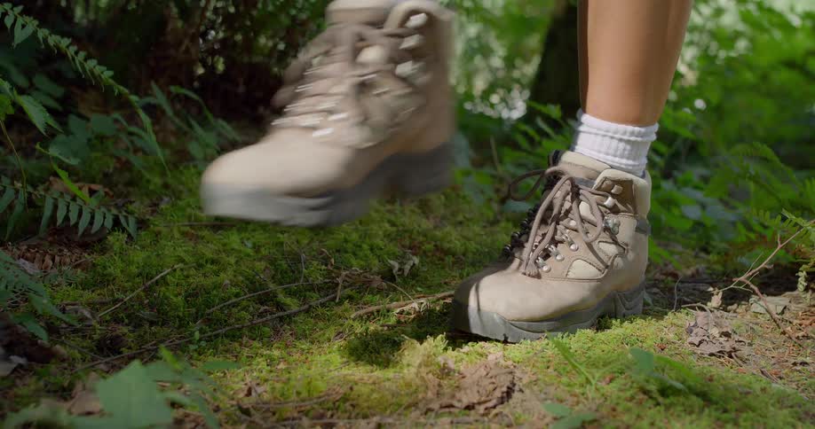Brown hiking boots walking on trail in the forest