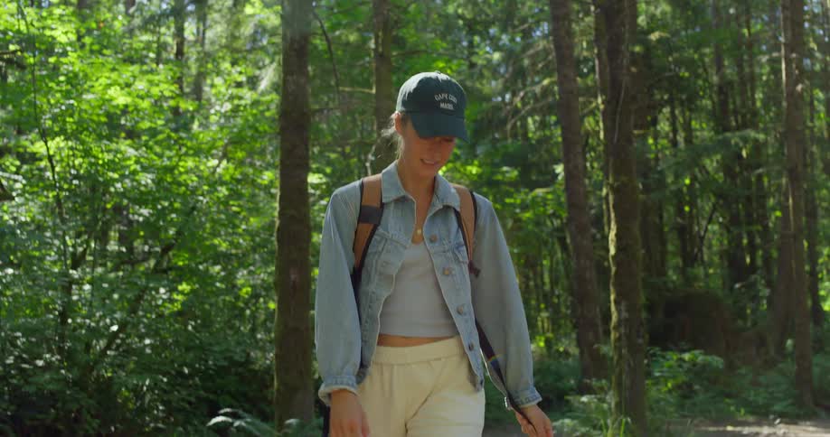 A woman looks happy as she looks around and hikes through a forest