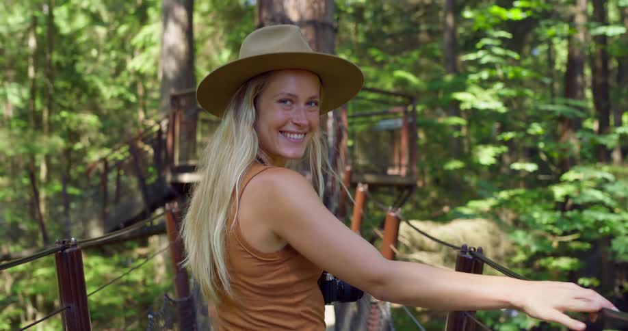 The woman is crossing the bridge high up in the forest