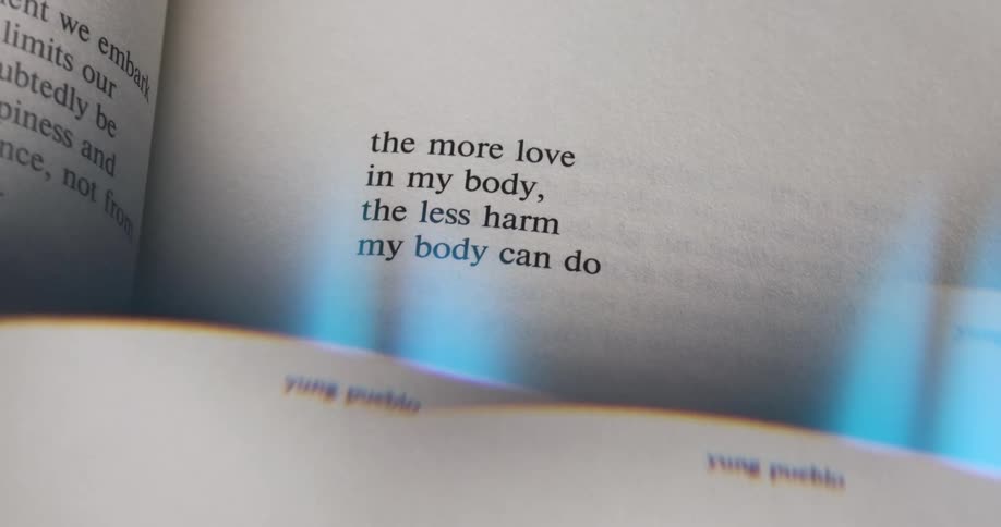 A closeup shot focuses on a short poem about love and less harm printed on the page of an open book