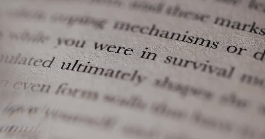 The camera is focused on an open book showing a page with text the words you were in survival are visible and in focus the surrounding text is slightly blurred