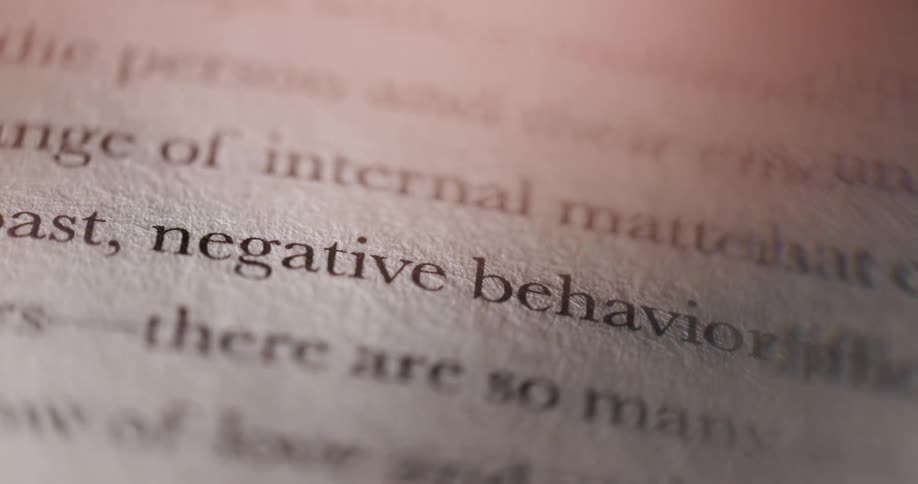 A closeup shot of book text focuses on the words negative behavior