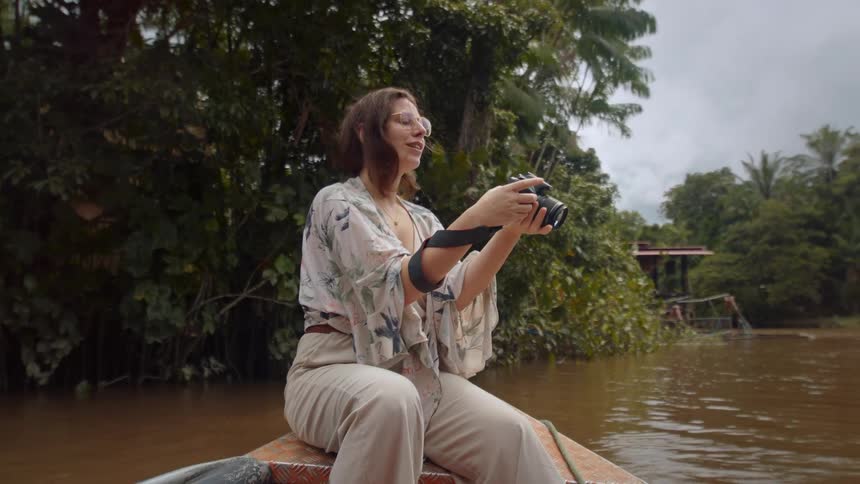 Close up of a young female adult photographer taking pictures while on canoe in a river during daytime