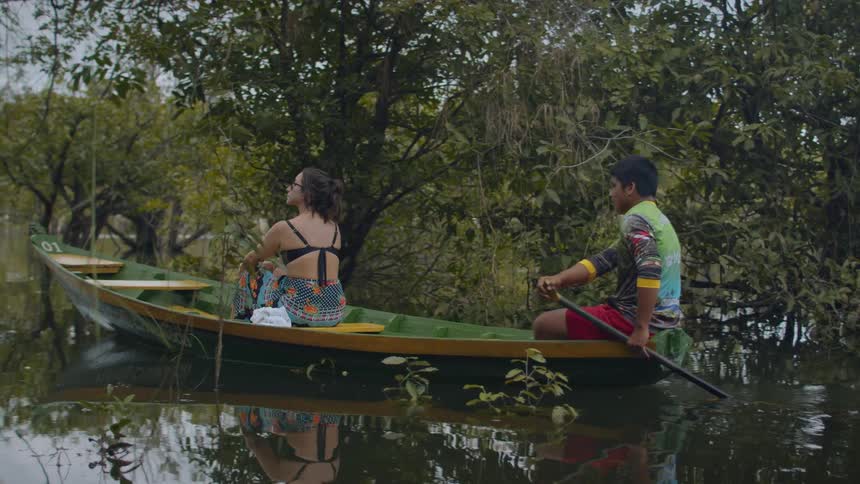 Woman sightseeing in a wooden boat accompanied by a man rowing