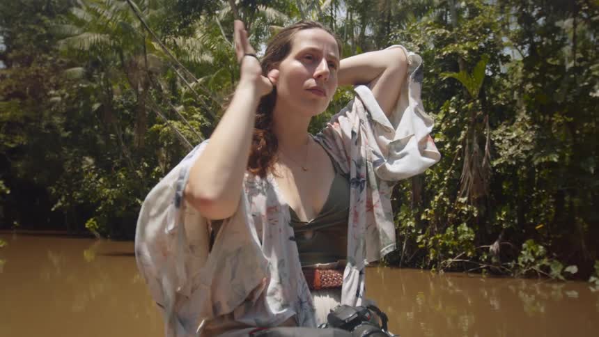 The woman ties her hair back while riding on the boat