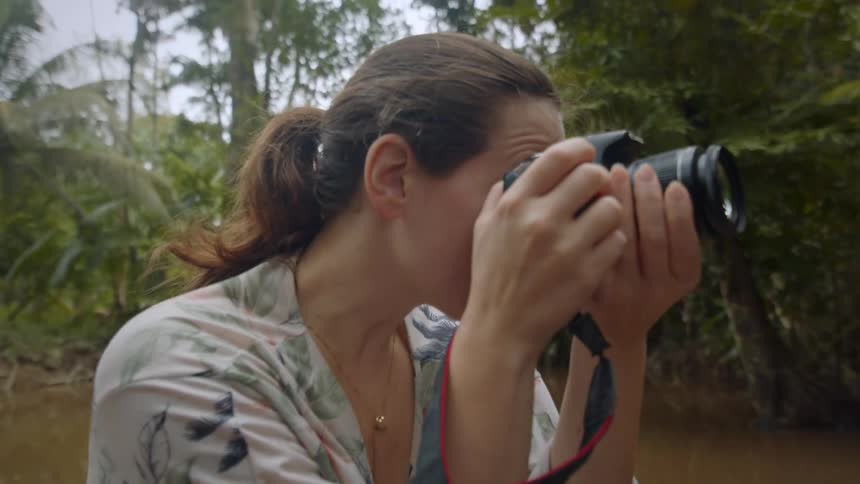A woman is using a camera to take photos in a swamp area