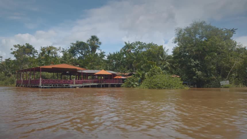 Floating restaurant by a river surrounded by tropical trees