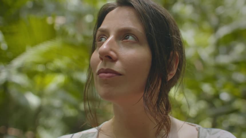 The woman is looking around the forest