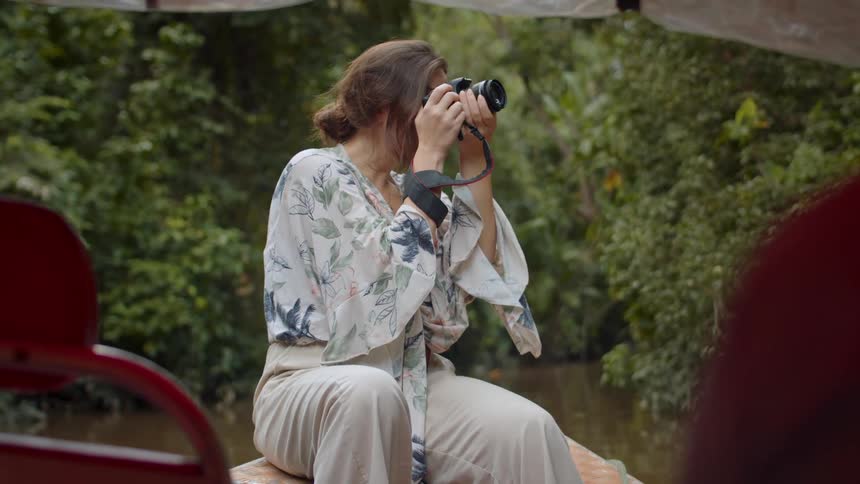 Woman takes photos from a small boat in the jungle