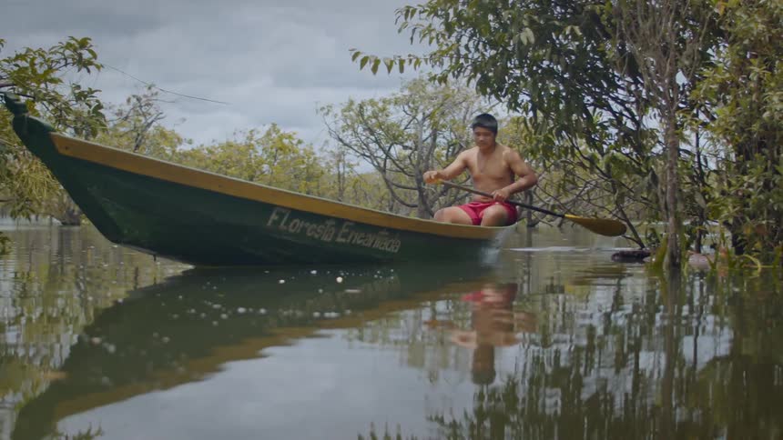 A man is rowing a long boat through the water