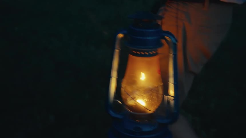 The video shows a person walking at night holding a lit oil lantern the lantern illuminates the immediate area as they move