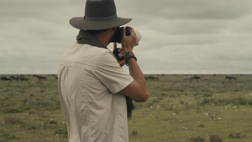 The man is taking photos of a running herd of animals