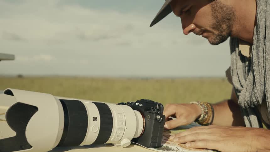 A photographer with a long lens camera is looking at a map