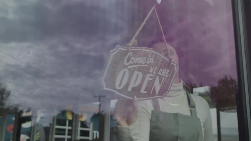 An employee flips a store sign to open