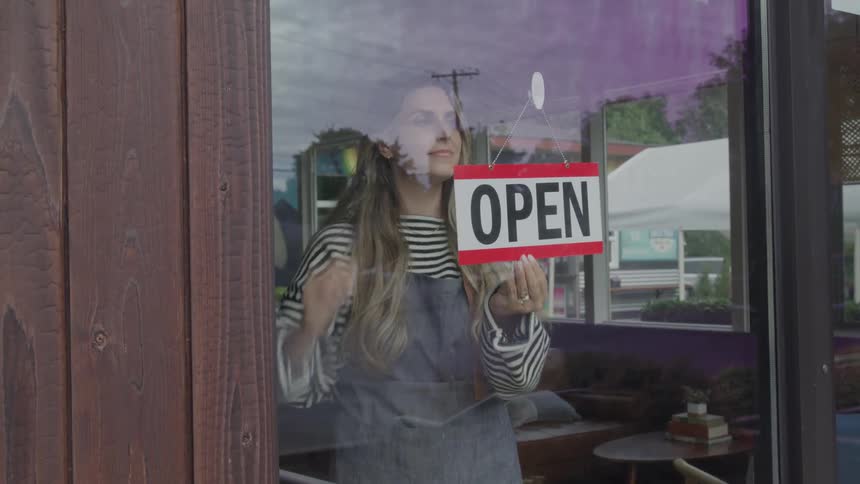 Woman opening a store with an open sign