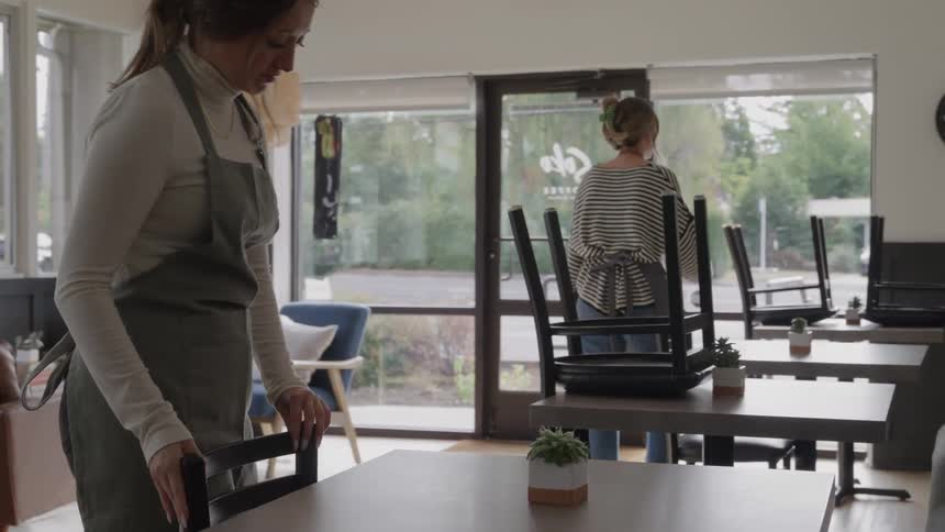 Two women set up the tables in the restaurant