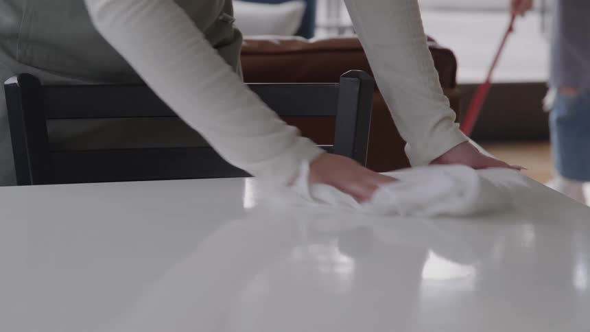 Restaurant employee wiping down a white table with a rag