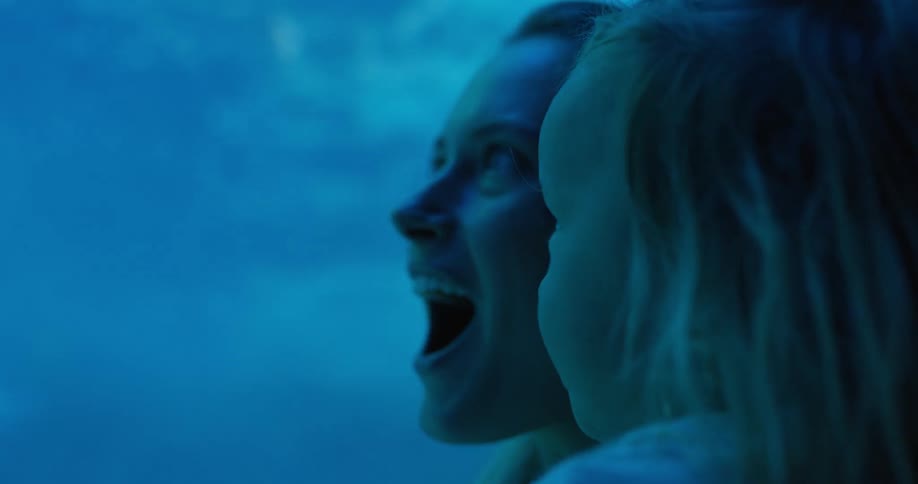 A mother and her young daughter are looking at something with wonder and excitement the scene is lit with a vibrant blue light